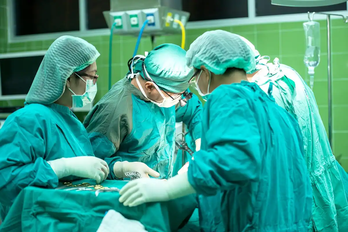 Echipă de chirurgi în sala de operație, intervenție acoperită de asigurarea de sănătate
