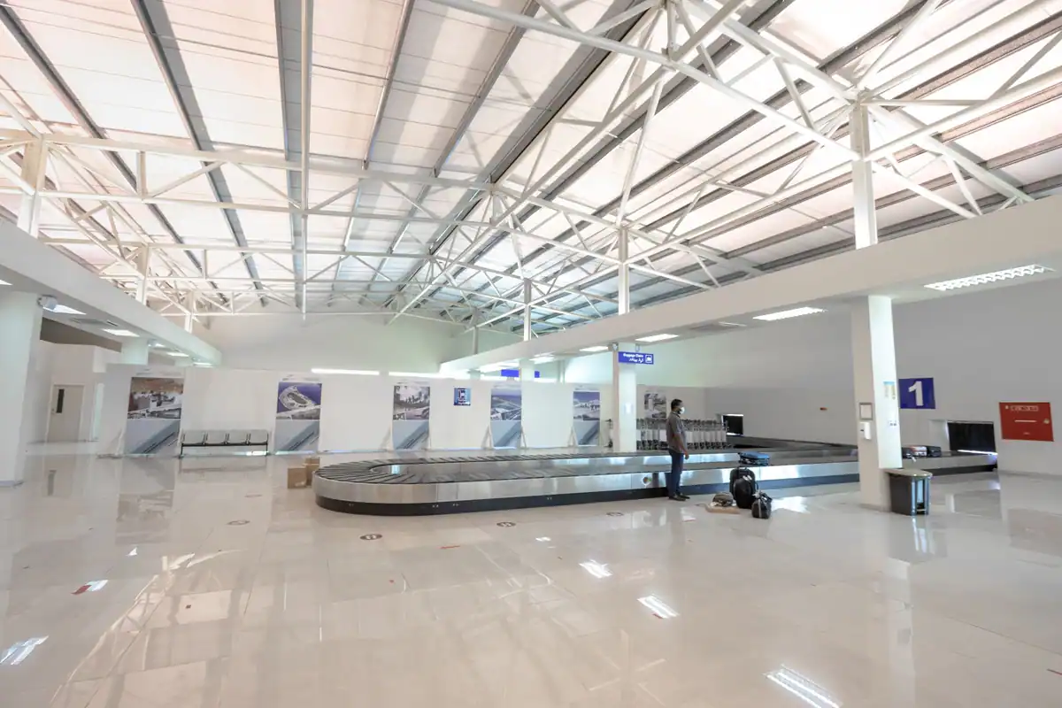 Sală de recuperare a bagajelor din aeroport, cu banda transportoare și un călător