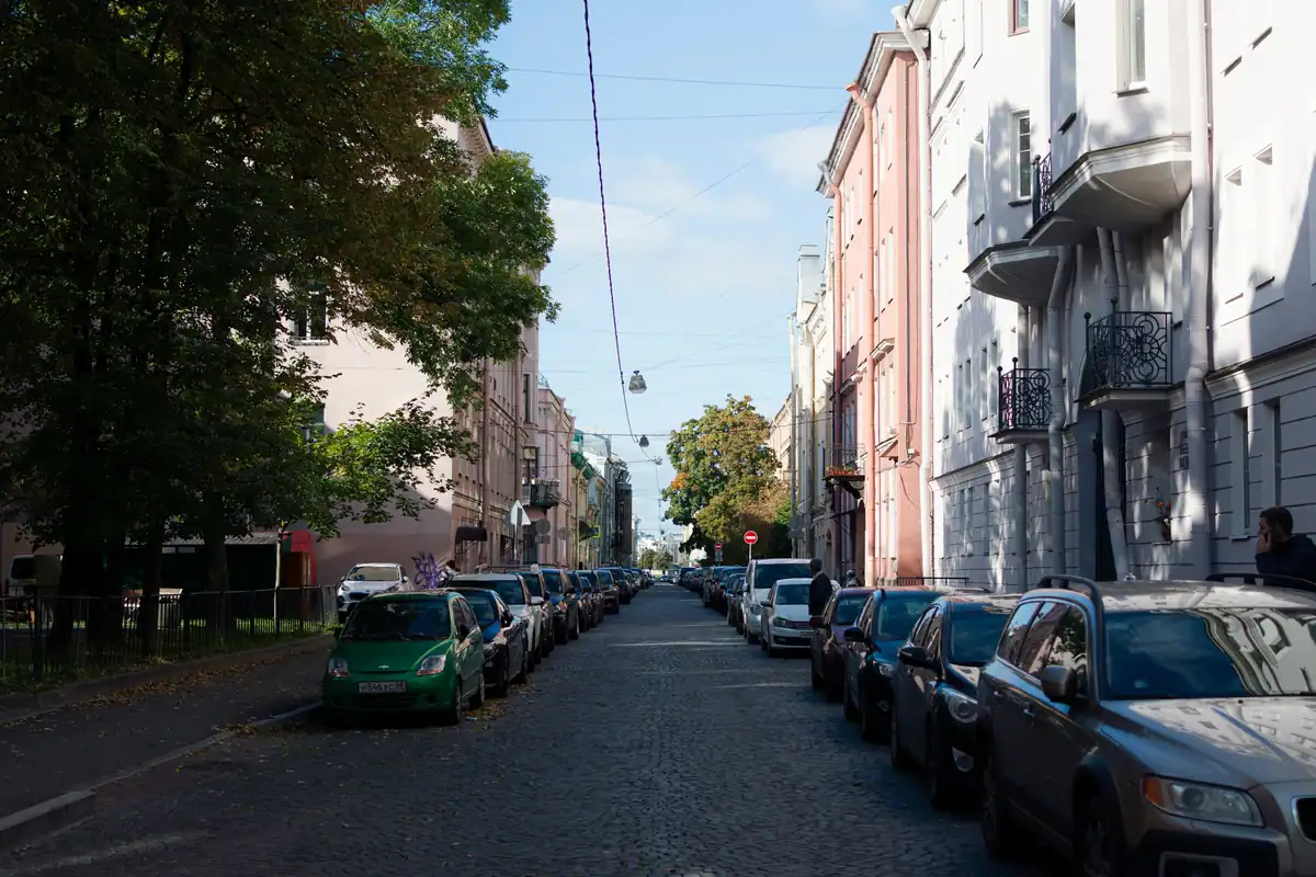 Stradă liniștită cu mașini parcate de-a lungul clădirilor vechi