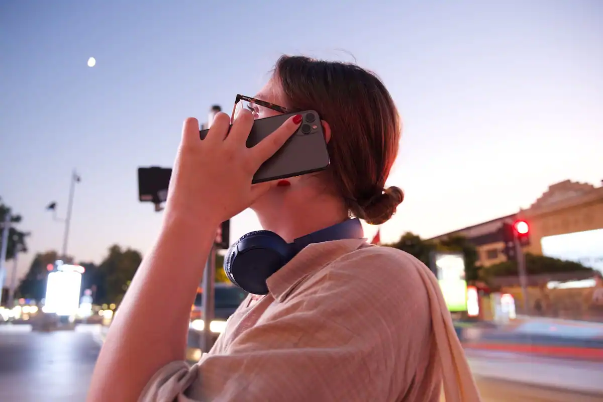 Turistă care sună la asistență cu telefonul, pe o stradă la amurg