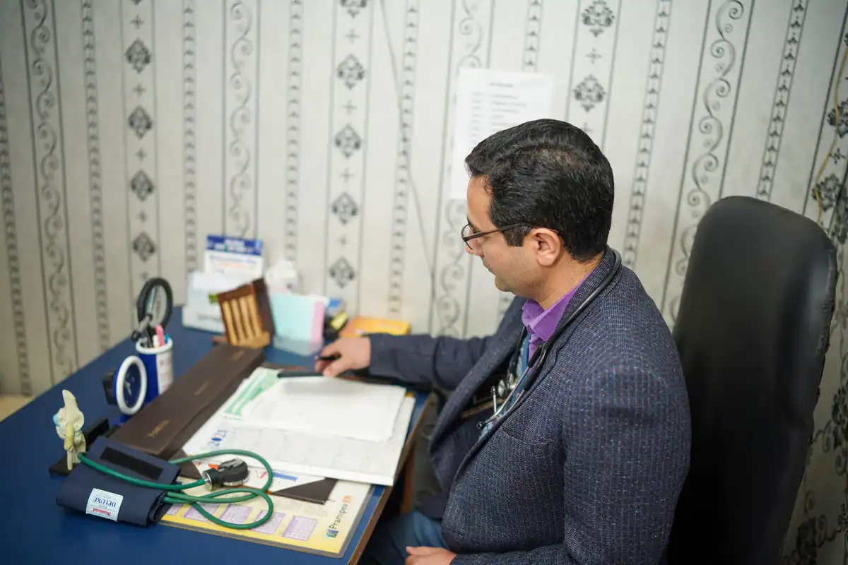 Medic care citește documentele unui pacient la biroul din cabinet