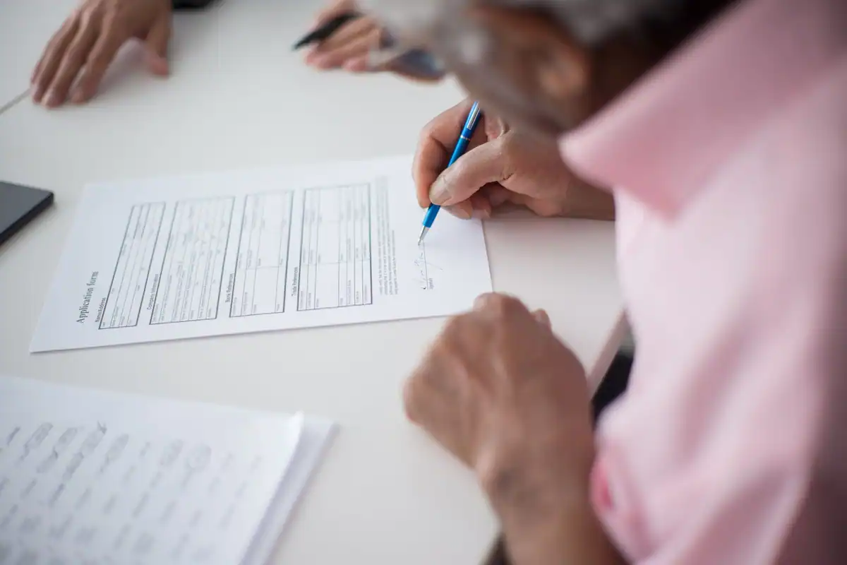 Bărbat în vârstă care semnează un formular la birou