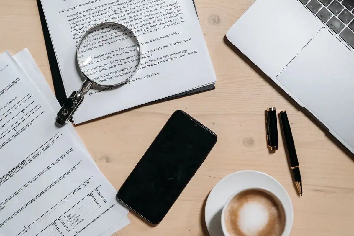 Documente, lupă, telefon și cafea pe un birou, pentru analiza contractului